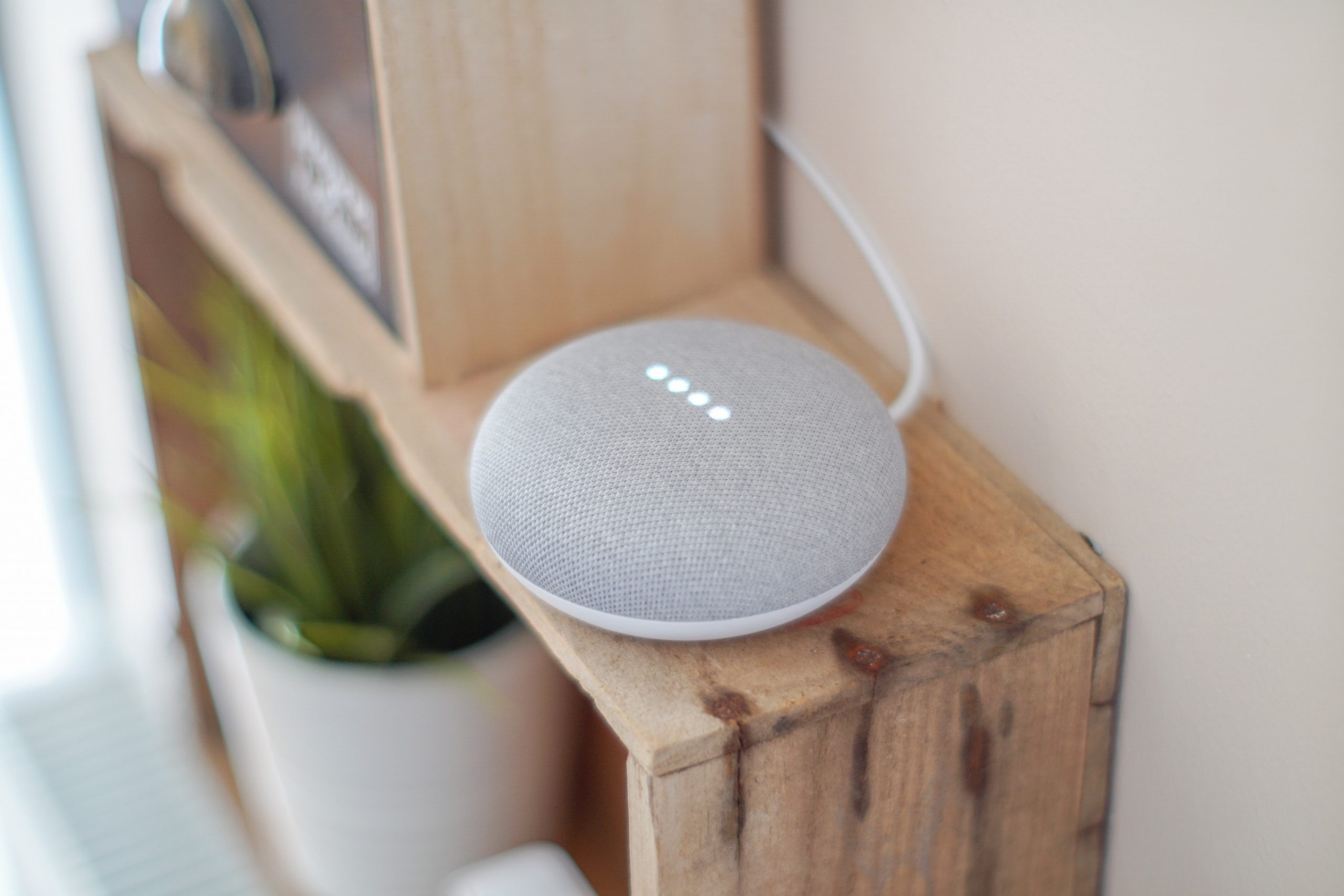 A white and gray speaker sitting on top of a wooden shelf.